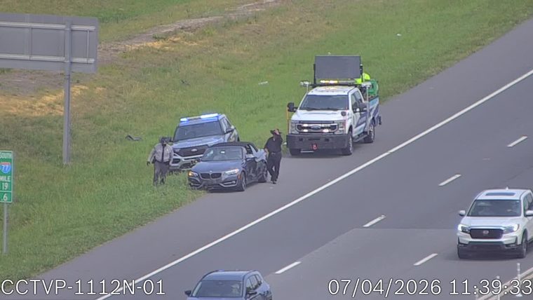 Police car and tow truck assisting a convertible on the right shoulder