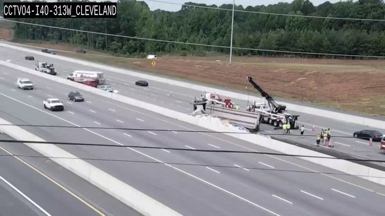 A tow truck and responders are at the scene of a trailer overturned on the highway.