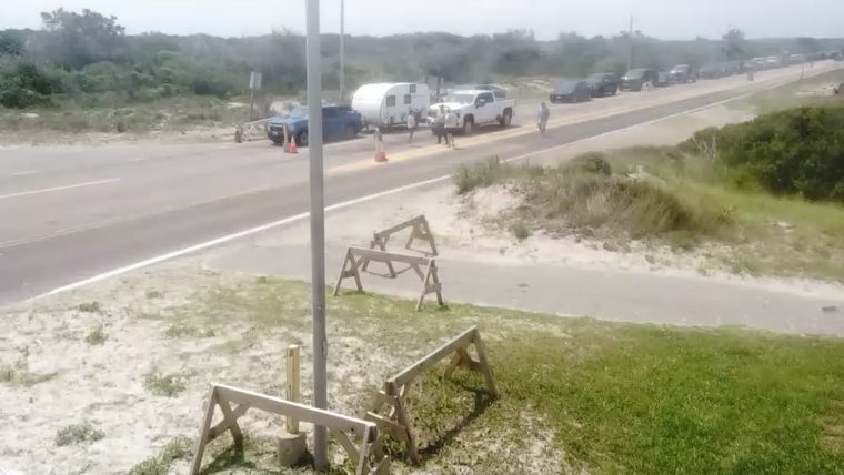 Traffic stopped due to a vehicle issue with people present and cones on the road.