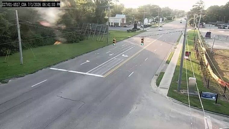 Fire and smoke in the grassy area to the left of the roadway