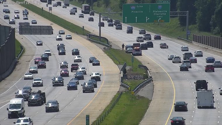 Police car and person on the shoulder of the highway.