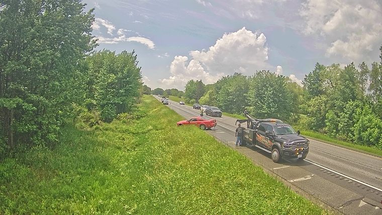 Tow truck and personnel assisting a car off the roadway.