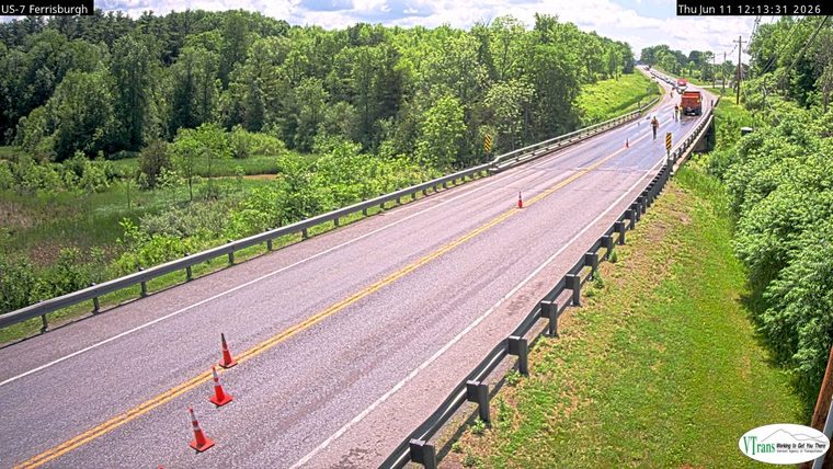 Road work with cones, a truck, and personnel on the roadway.
