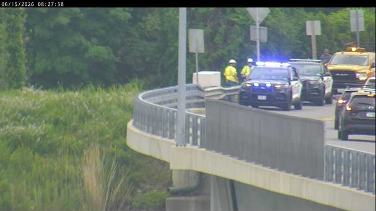 Police and other responders are present on the roadway with emergency lights active.