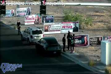 Multiple pedestrians standing on the shoulder next to two parked vehicles