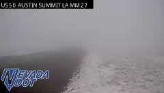 Heavy fog causing extremely low visibility on the roadway with snow on the shoulder