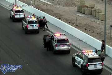 Three police cars with lights on and officers interacting with individuals