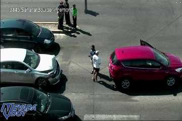 Two-vehicle crash in the intersection with front-end damage to a silver sedan, an open door on a red SUV, and multiple people standing in the roadway.