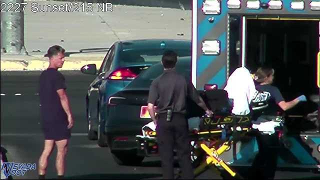 Ambulance and personnel attending to a patient on a stretcher next to a car