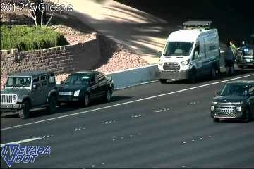 White van and a police vehicle on the right shoulder with people standing nearby