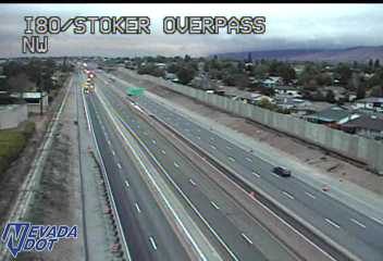 Construction vehicles with flashing lights and traffic cones along the left shoulder