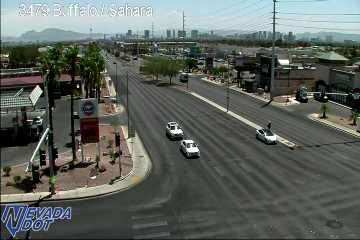 Pedestrian walking in the roadway near a white car on the right side of the road