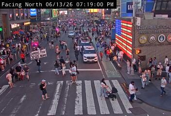 Police vehicles and personnel responding to a large gathering on a city street.