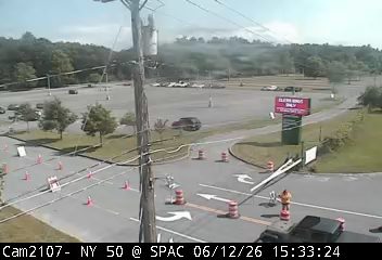 Person in orange vest directing traffic around cones and cones on the road.
