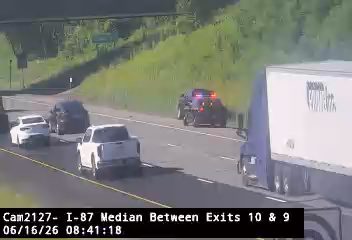 Police car with lights on, stopped on the highway median.