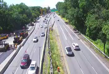 Construction vehicles and personnel are present on the side of the highway.