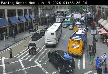 Police officer directing traffic at an intersection with multiple buses and cars.