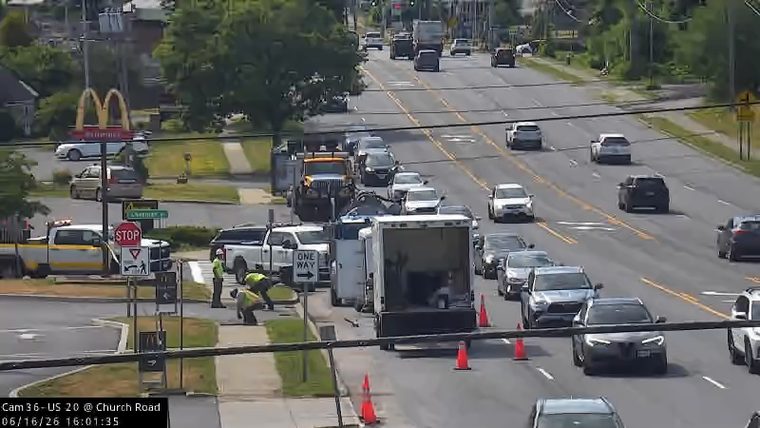 Road work with personnel and vehicles on the shoulder, traffic is moving.