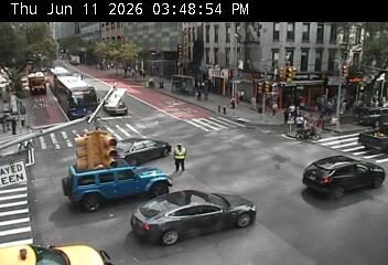 A person in a safety vest is standing near a traffic light that has fallen.