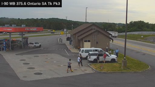 Tow truck and people gathered around vehicles at a gas station.