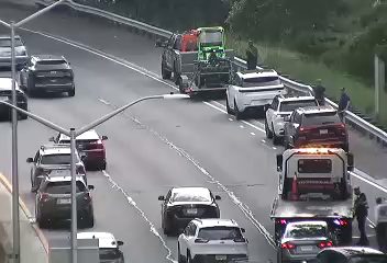 Tow truck and other vehicles stopped on the highway with personnel present.