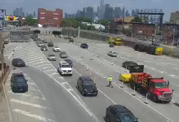 Worker in hi-vis vest directing traffic near construction equipment on highway.