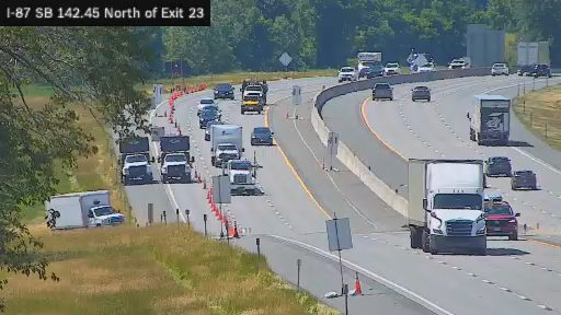 Debris on the roadway, traffic cones and stopped vehicles indicate a potential incident.