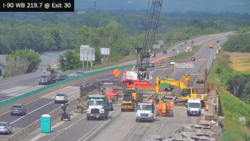 Construction zone with crane, trucks, and equipment on the highway.