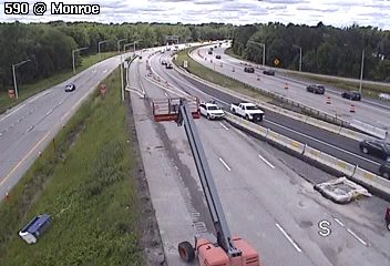 Construction vehicle and personnel on the highway shoulder, possibly responding to an incident.