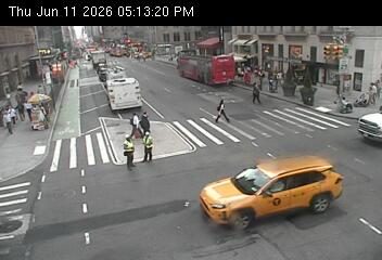Two individuals in safety vests appear to be directing traffic near a crosswalk.