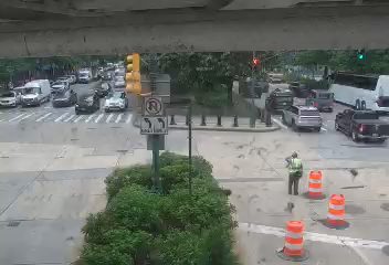A person in a safety vest is directing traffic near cones.