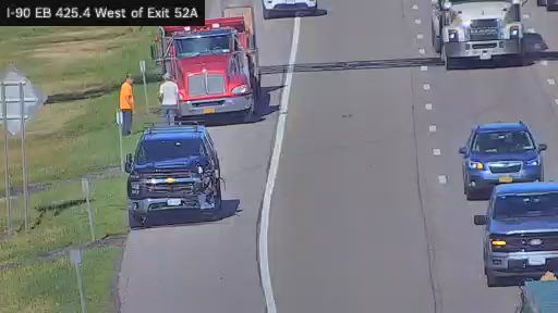 Two people standing by a truck on the shoulder of the highway.
