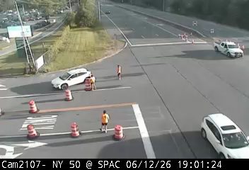 Police vehicle and personnel on scene with traffic cones.