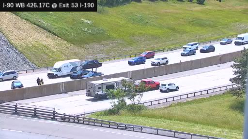 Two people in uniform are attending to a vehicle on the shoulder of the highway.