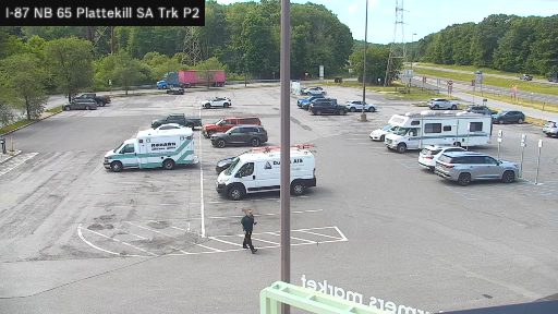 Ambulance and other vehicles present in parking lot, person walking.