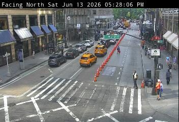 Police officer directing traffic around cones on a city street.