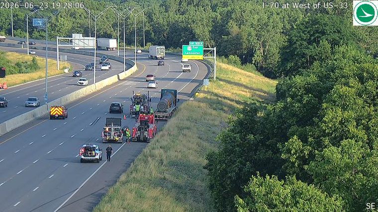 Police car and multiple tow trucks with personnel on the right shoulder