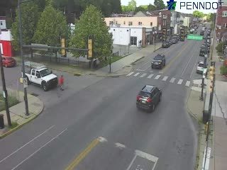 A person in orange is standing near a white truck, possibly directing traffic.