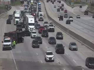Two workers are attending to a white truck on the side of the highway.