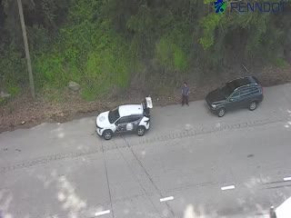Two vehicles and a person are stopped on the side of the road.