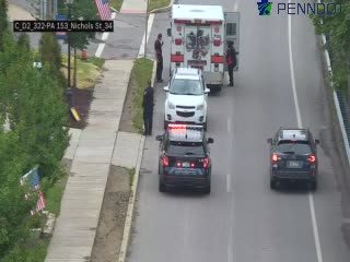 Ambulance and police vehicles on the roadside with personnel present.