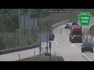 Police car and person on the shoulder near the highway.