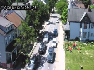 Several people in orange vests appear to be responding to an incident on the side of the road.