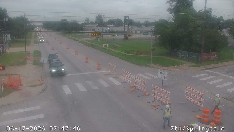 Road closed with construction workers present at intersection.