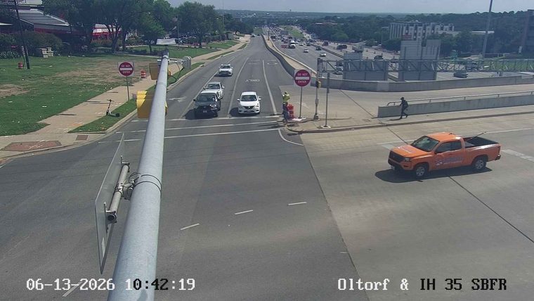 Person in reflective vest near traffic cones and a vehicle.
