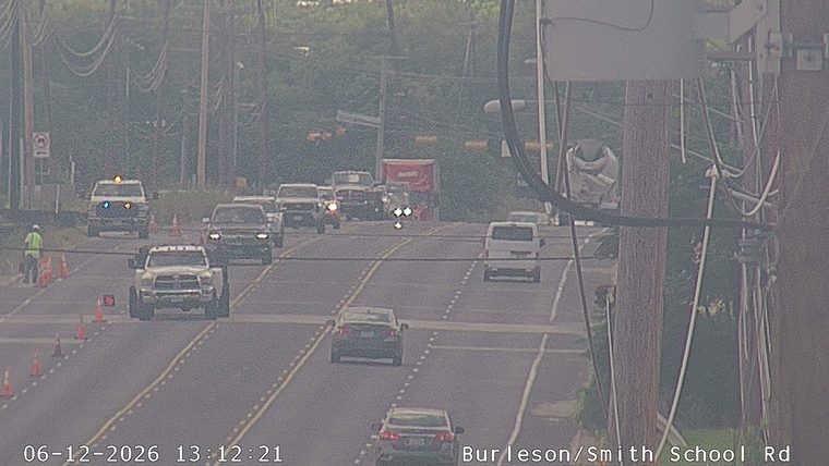 Traffic cones and a worker indicate a possible incident or road work ahead.