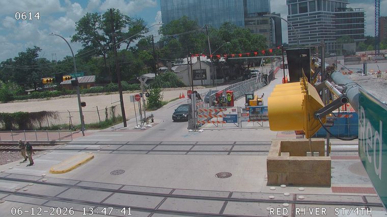 Construction workers and equipment are present at a road closure with barriers.