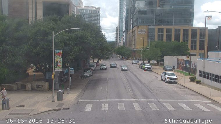 Two white trucks and two cones are on the right side of the road.