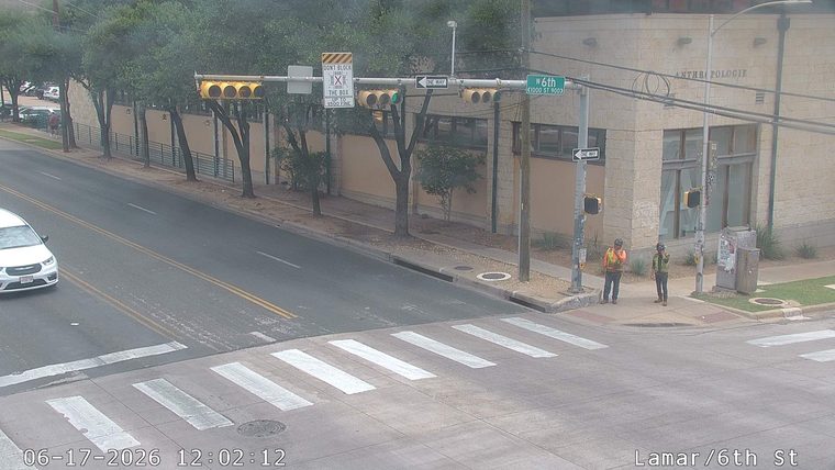 Two workers in safety vests are standing at the intersection.