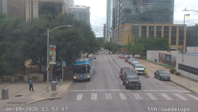 Worker in reflective vest directing traffic near parked vehicles.